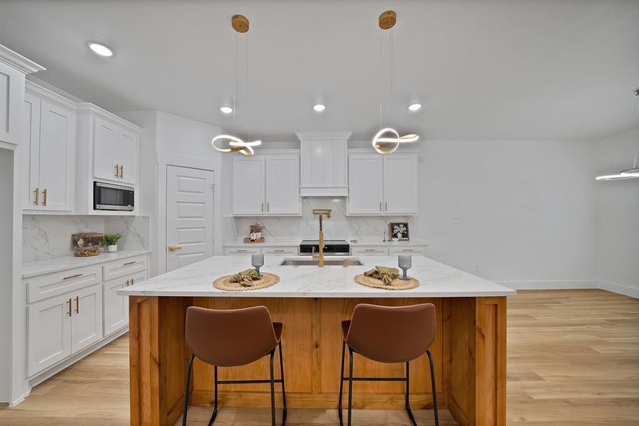 Kitchen featuring light stone counters, decorative light fixtures, backsplash, a kitchen breakfast bar, and recessed lighting