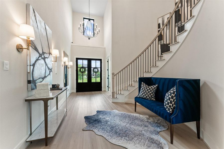 The foyer offers a dramatic first impression with tall ceilings, stair detail, and designer sconces. Clean sight lines create a natural connection to the main living spaces beyond.