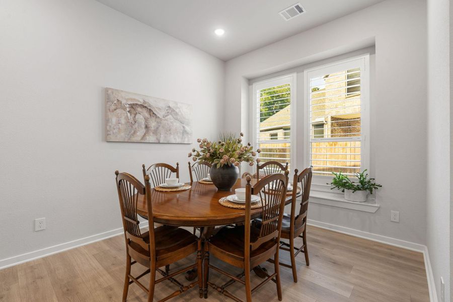 Dining area just off the kitchen with expansive windows with shutters and views of the side yard.