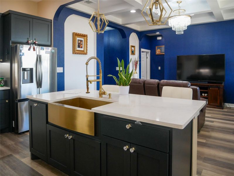 Kitchen featuring arched walkways, coffered ceiling, dark wood finished floors, stainless steel fridge, and a chandelier