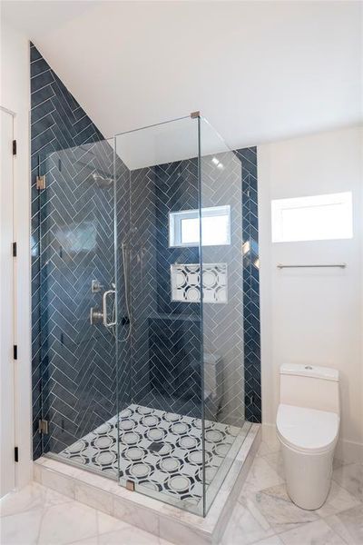 Bathroom featuring a shower with door and toilet