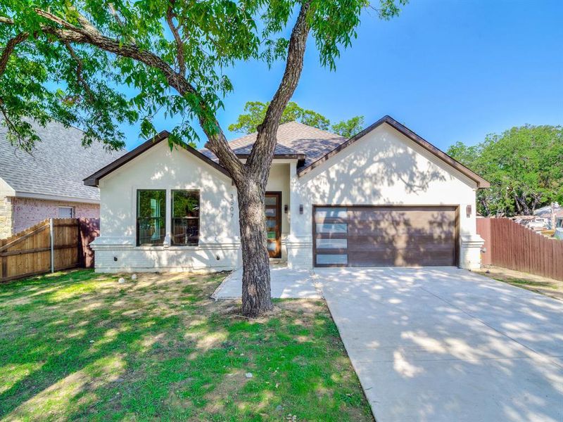 View of front of property featuring a garage and a front lawn