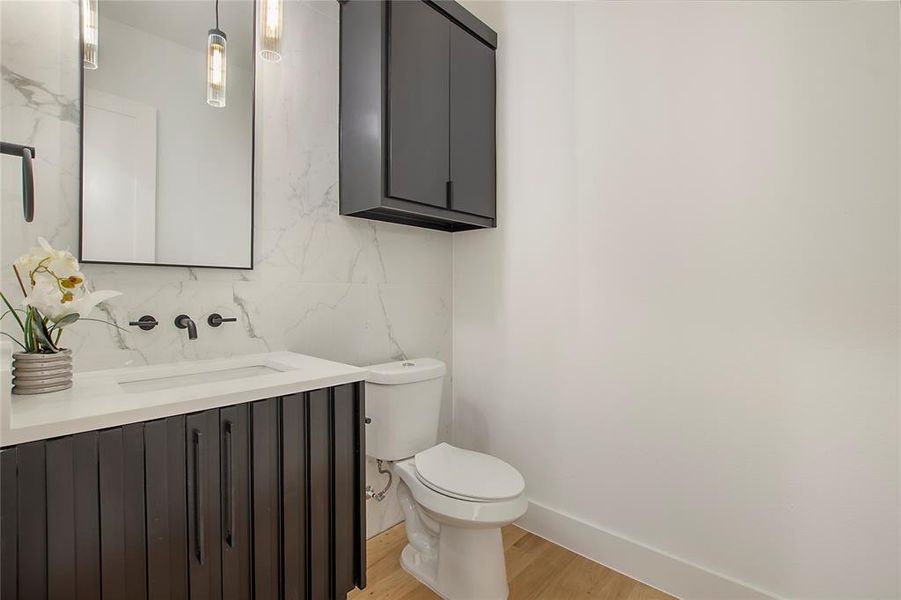 Bathroom featuring vanity, wood-type flooring, toilet, and tasteful backsplash