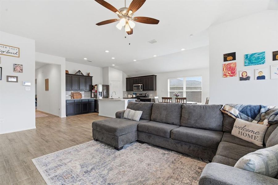 Living room with vaulted ceiling, light wood-type flooring, ceiling fan, and recessed lighting
