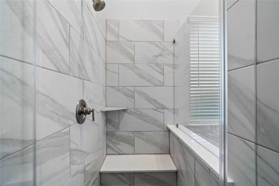 The walk-in shower includes a convenient, integrated white bench and a shelf, offering comfort, extra storage space, and a high-end, custom appearance. The walk-in shower includes a convenient, integrated white bench and a shelf, offering comfort, extra storage space, and a high-end, custom appearance.