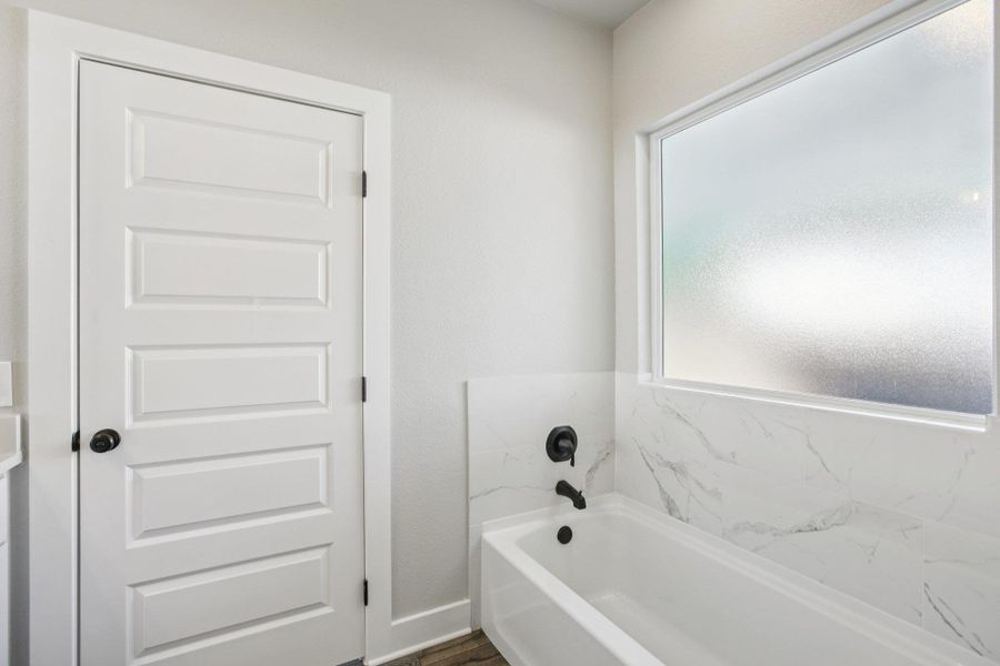 Full bath with a garden tub and dark wood-style flooring