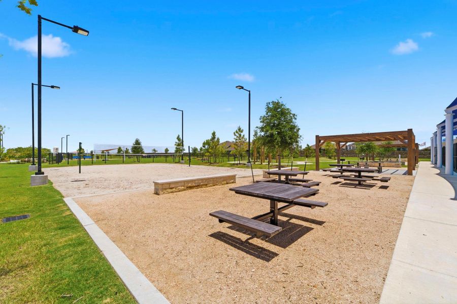 Resort-style sand volleyball court with shaded picnic areas, perfect for recreation and outdoor gatherings.