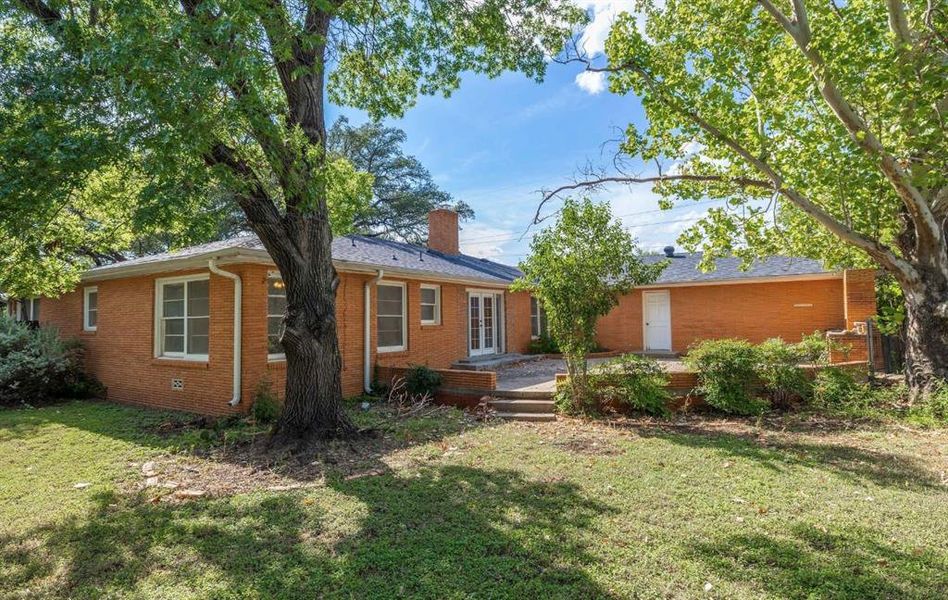 Back of house with a lawn, brick siding, and a chimney