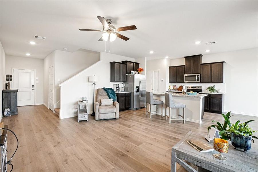 Living area with recessed lighting, light wood finished floors, a ceiling fan, and stairway Living area with recessed lighting, light wood finished floors, a ceiling fan, and stairway
