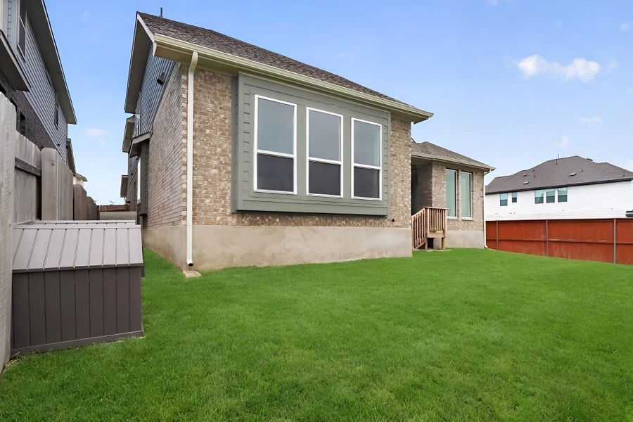 Expansive green lawn with a brick exterior, a bay window with trim, a wooden deck, and a wooden privacy fence Expansive green lawn with a brick exterior, a bay window with trim, a wooden deck, and a wooden privacy fence