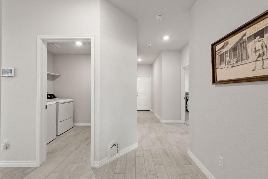 Hall with light wood finished floors, separate washer and dryer, and recessed lighting