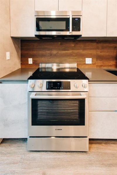 Kitchen featuring appliances with stainless steel finishes, light wood-type flooring, and white cabinets