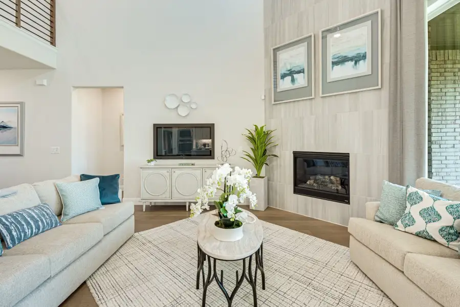 Living room with two-story ceiling, tile fireplace, two sofas, and hardwood floors