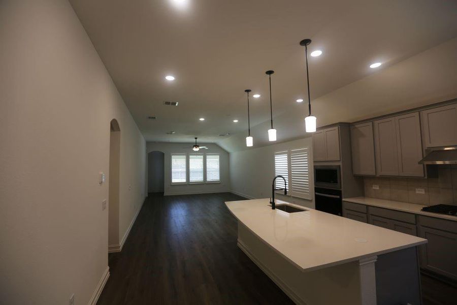 Modern kitchen featuring light gray cabinetry, built-in appliances, and a central island with a white countertop and undermount sink