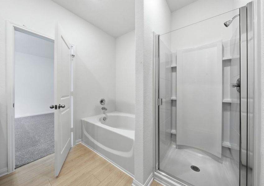 Primary bathroom featuring a garden tub and a separate glass-enclosed walk-in shower. Primary bathroom featuring a garden tub and a separate glass-enclosed walk-in shower.