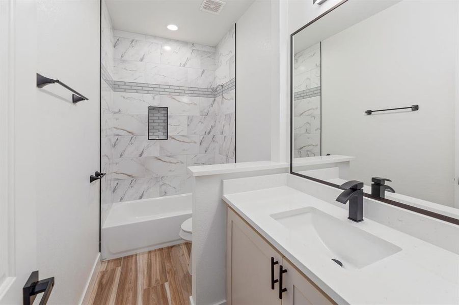 Bathroom with visible vents, toilet, wood finished floors, tub / shower combination, and vanity