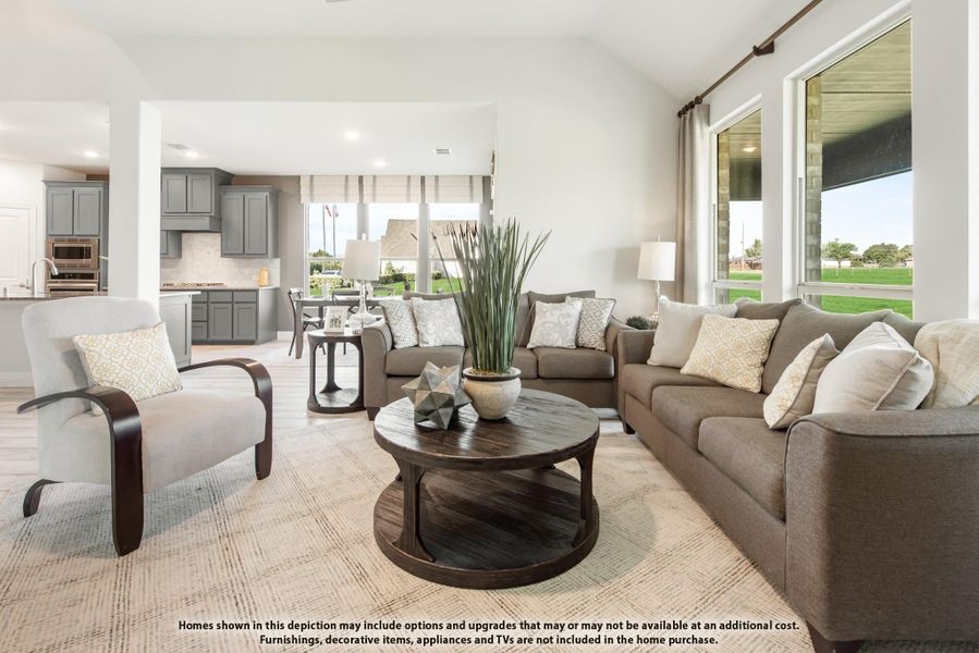 Open-concept living room with gray sofas, round wood coffee table, and kitchen visible in background