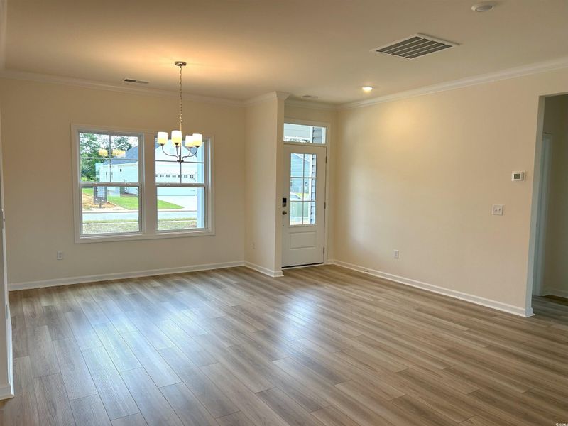 Unfurnished dining area with a chandelier, ornamental molding, and wood finished floors