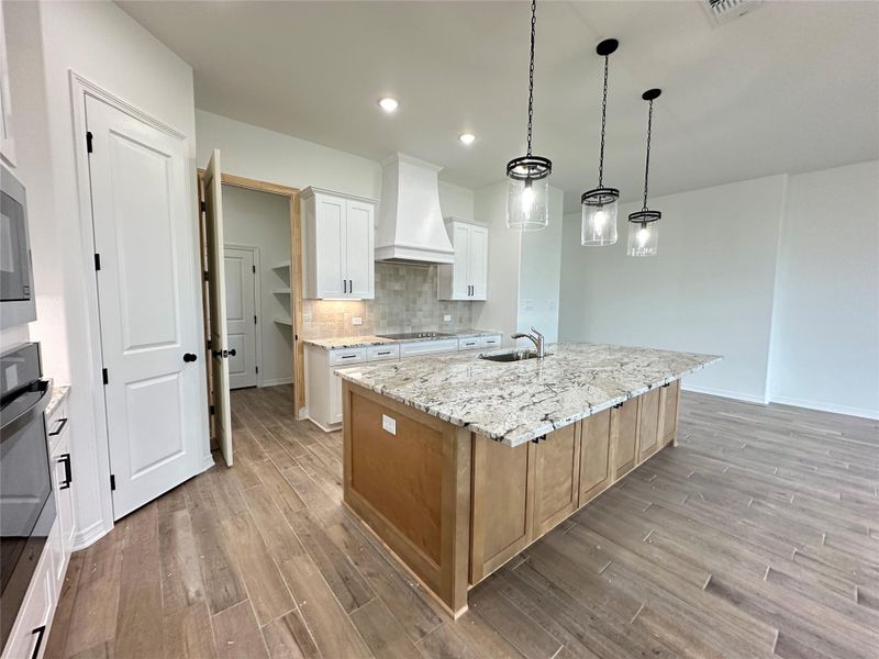 Kitchen featuring light stone counters, tasteful backsplash, decorative light fixtures, stainless steel appliances, and white cabinets