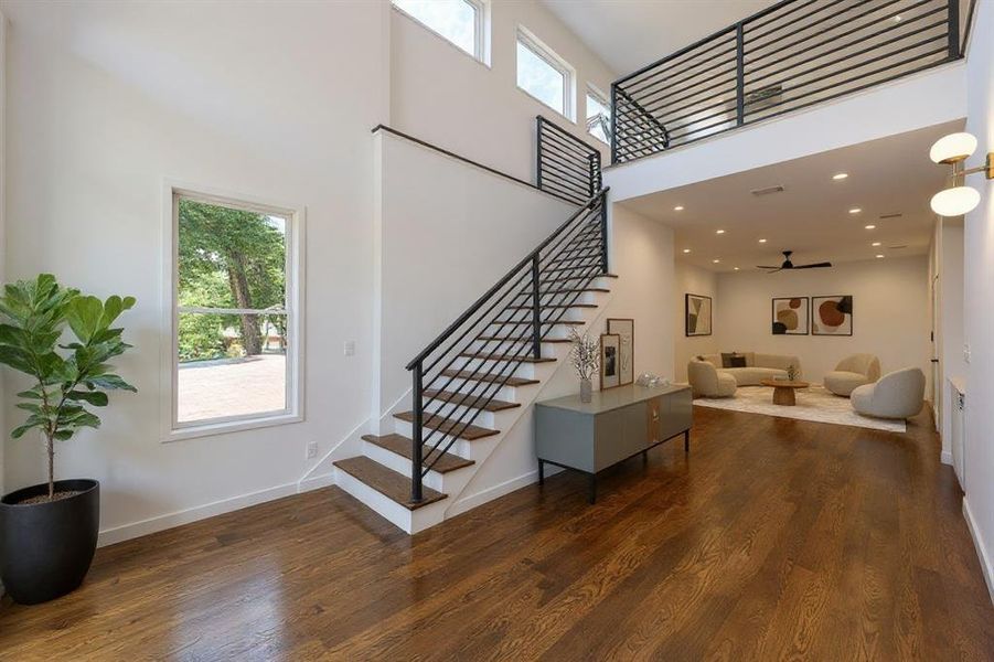 Stairway featuring a high ceiling, wood finished floors, and recessed lighting