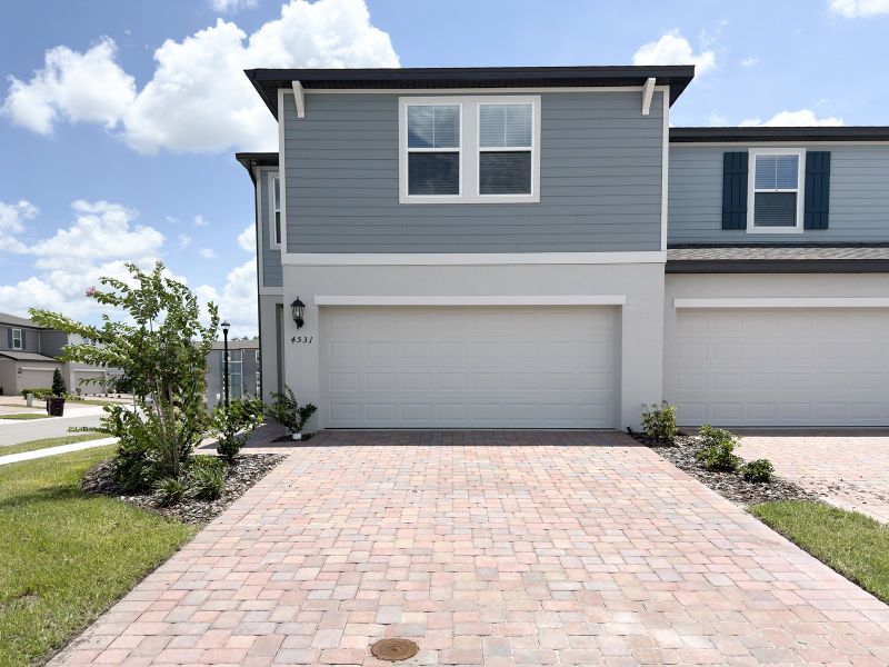 Front exterior of a new home in The Meadow at Crossprairie Townes, St. Cloud, FL, highlighting curb appeal (Image 1). Front exterior of a new home in The Meadow at Crossprairie Townes, St. Cloud, FL, highlighting curb appeal (Image 1).