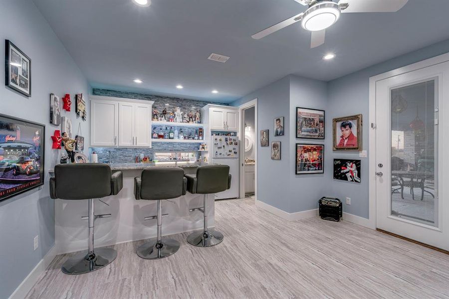 Bar features cabinets, ice maker, and island with lots of storage and seating