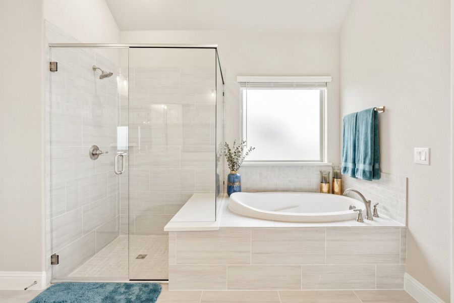 Master bathroom with glass walk-in shower, soaking tub, and light tile floors