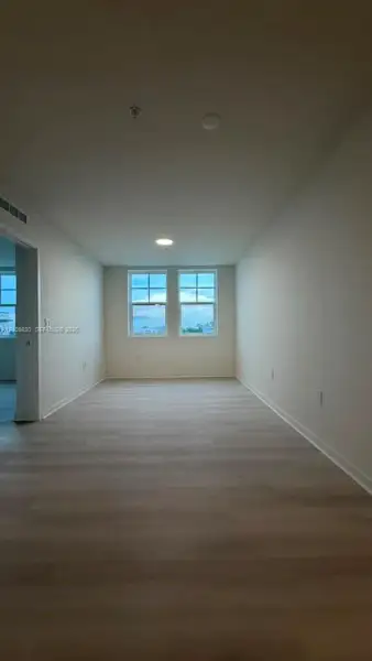 Interior space featuring wood-finish flooring, neutral wall tones, dual windows, and ceiling-mounted lighting
