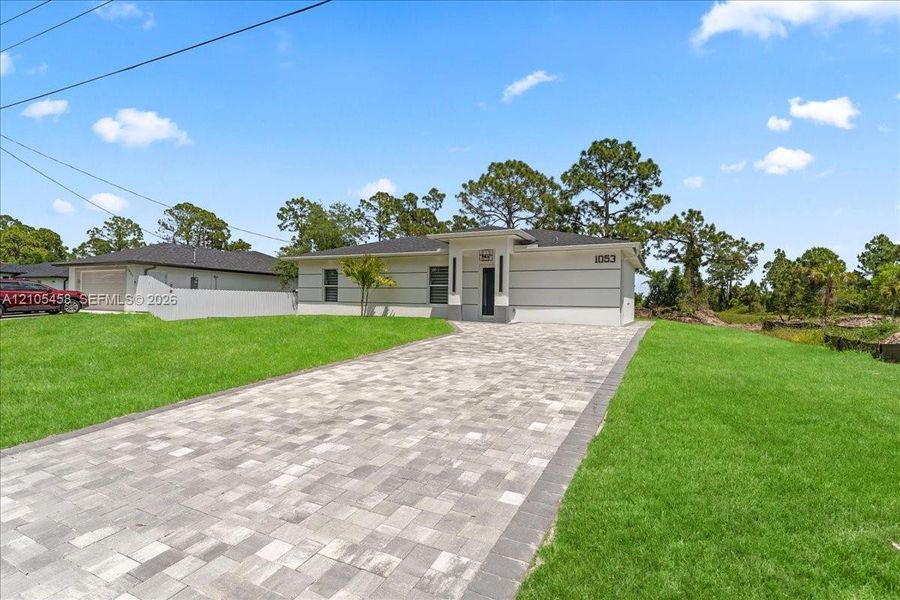 Modern-style exterior with gray siding, white trim, and a paver driveway Modern-style exterior with gray siding, white trim, and a paver driveway