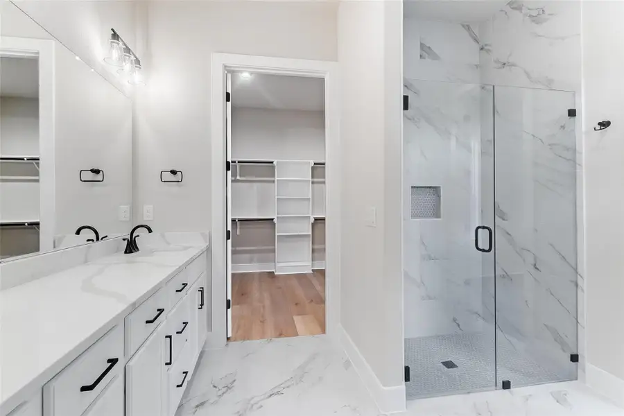 Full bathroom featuring a walk in closet, a marble finish shower, vanity, and light marble finish floors
