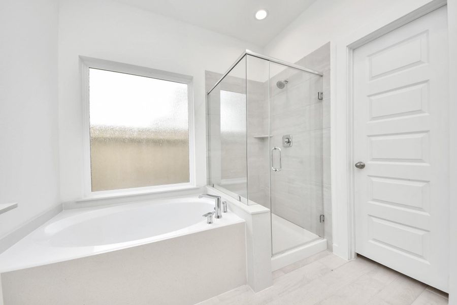 Indulge in a spa-like retreat within the confines of this primary bathroom. Delight in a spacious walk-in shower enveloped in stylish tile surround, unwind in a separate garden tub adorned with custom detailing. Indulge in a spa-like retreat within the confines of this primary bathroom. Delight in a spacious walk-in shower enveloped in stylish tile surround, unwind in a separate garden tub adorned with custom detailing.