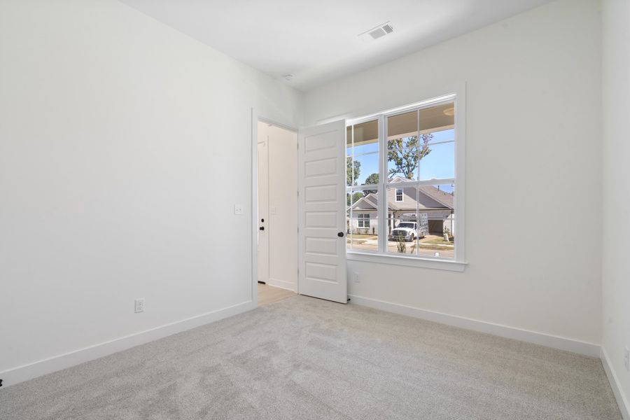 Neutral-toned wall-to-wall carpeting, multi-pane window, and six-panel interior door Neutral-toned wall-to-wall carpeting, multi-pane window, and six-panel interior door