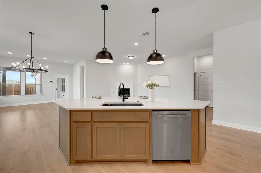 Kitchen with dishwasher, light wood finished floors, a center island with sink, and open floor plan