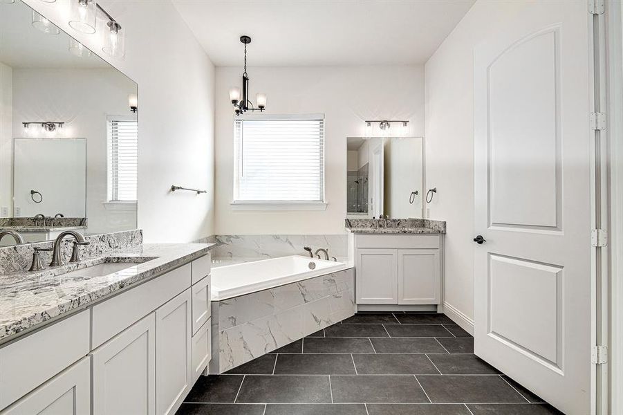 Bathroom featuring tile patterned flooring, vanity, tiled bath, and a chandelier