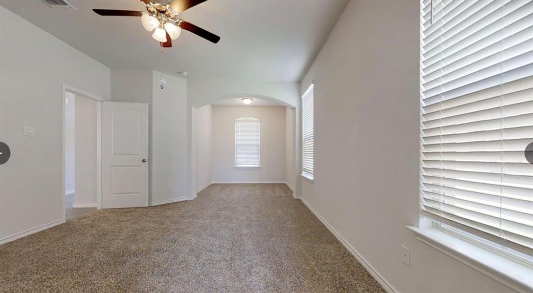 Empty room featuring ceiling fan, carpet flooring, arched walkways, and baseboards