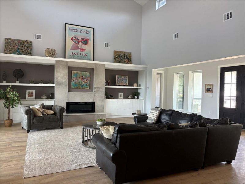 A spacious living room with soaring vaulted ceilings and built-in shelving flanking a sleek, modern fireplace.