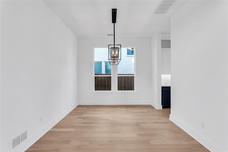 Unfurnished dining area featuring light wood-style flooring and a chandelier