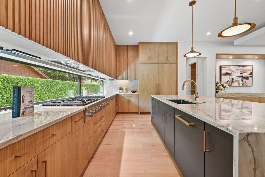 Kitchen featuring light stone counters, light wood-style floors, decorative light fixtures, modern cabinets, and recessed lighting