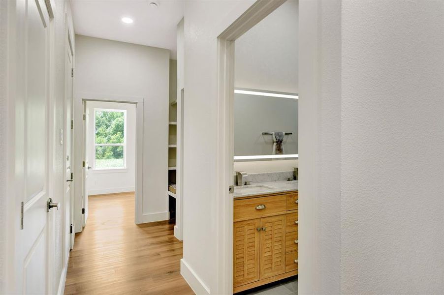 Bright hallway featuring wood-finish flooring, recessed lighting, and white paneled doors Bright hallway featuring wood-finish flooring, recessed lighting, and white paneled doors