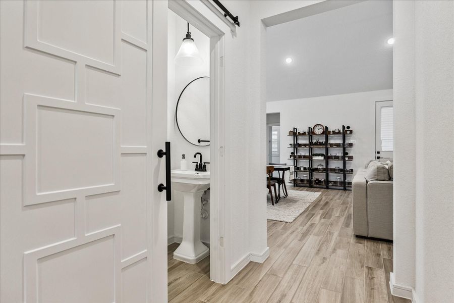 Designer powder bath conveniently positioned off the main hallway, featuring modern lighting, matte black fixtures, and a sleek contemporary aesthetic.