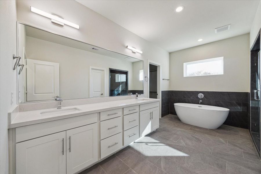 A spacious double vanity with modern finishes offers plenty of storage and counter space for a clean, organized start to every morning.