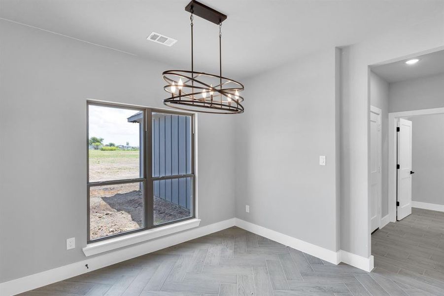 Unfurnished dining area featuring baseboards and a chandelier