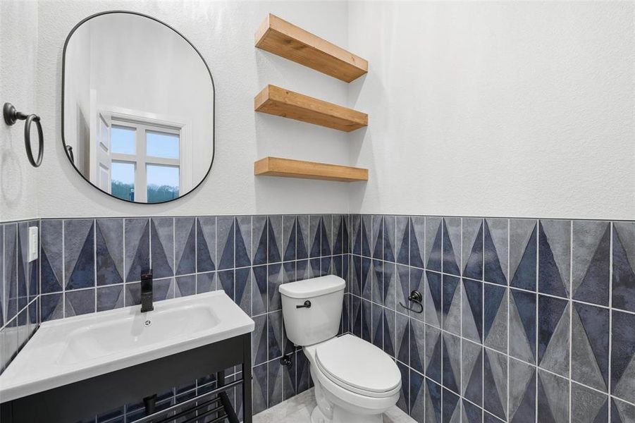 Bathroom featuring tile walls, a wainscoted wall, and a textured wall Bathroom featuring tile walls, a wainscoted wall, and a textured wall