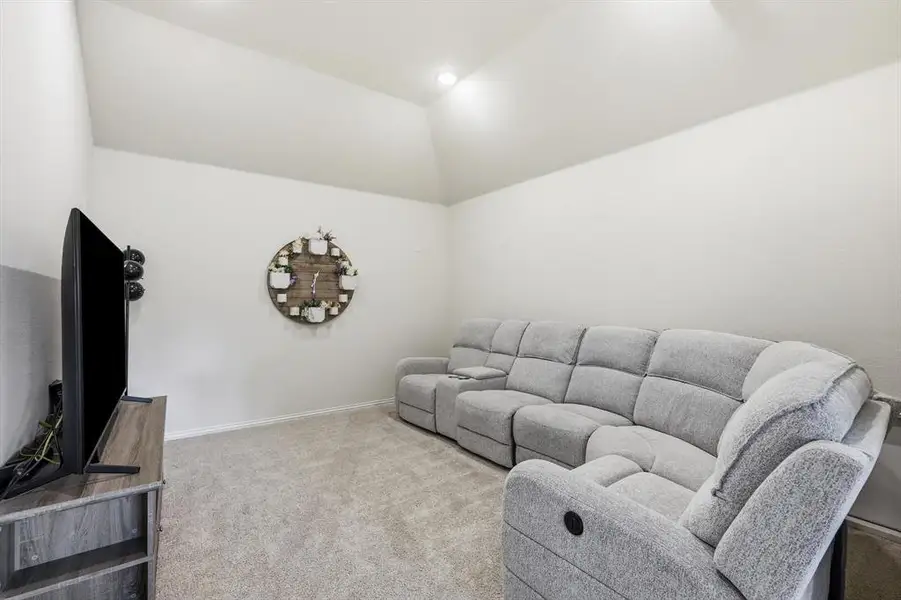 Carpeted media room featuring vaulted ceilings, light-colored walls, and recessed lighting