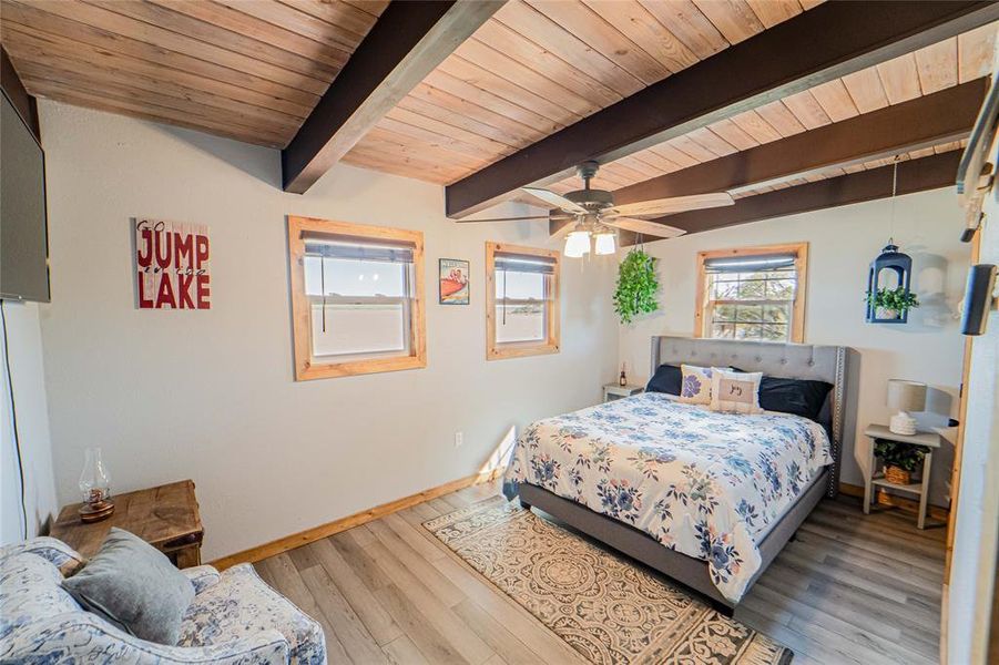 Bedroom featuring light wood-style floors, a ceiling fan, and a wooden ceiling with exposed beams Bedroom featuring light wood-style floors, a ceiling fan, and a wooden ceiling with exposed beams