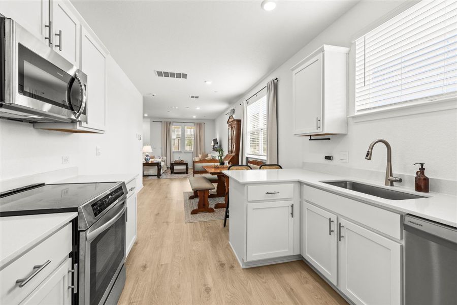An open-concept living space integrates a pristine kitchen, dining area, and well-lit sitting room.