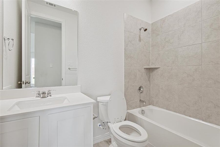 Full bathroom with toilet, tiled shower / bath, and vanity