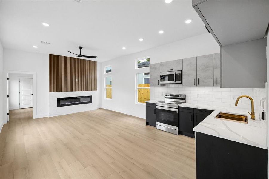 Kitchen featuring appliances with stainless steel finishes, ceiling fan, recessed lighting, decorative backsplash, and light stone countertops