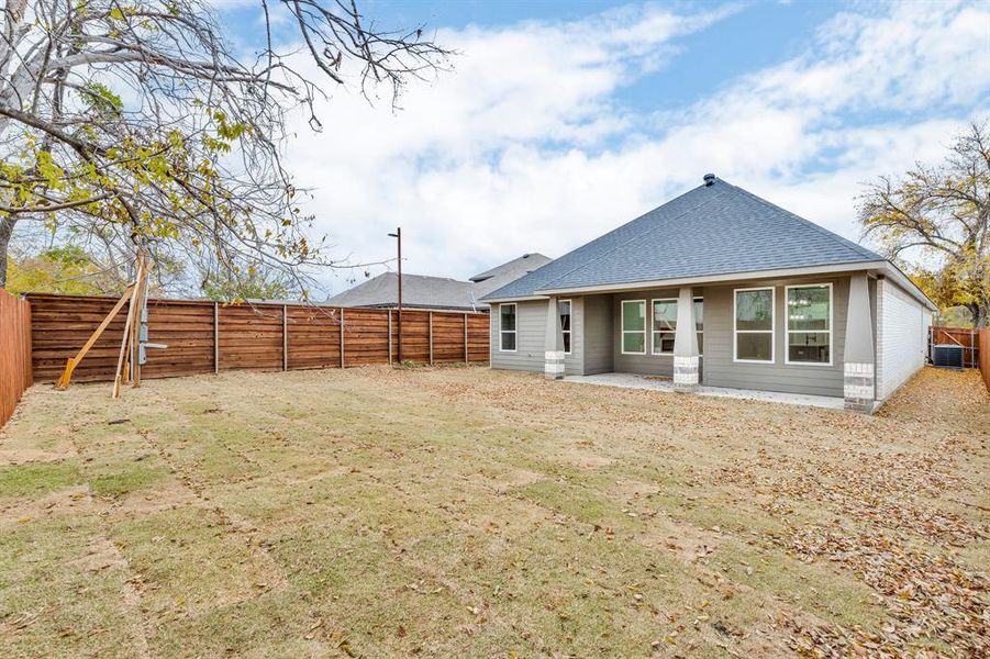 Back of property with a yard and central air condition unit