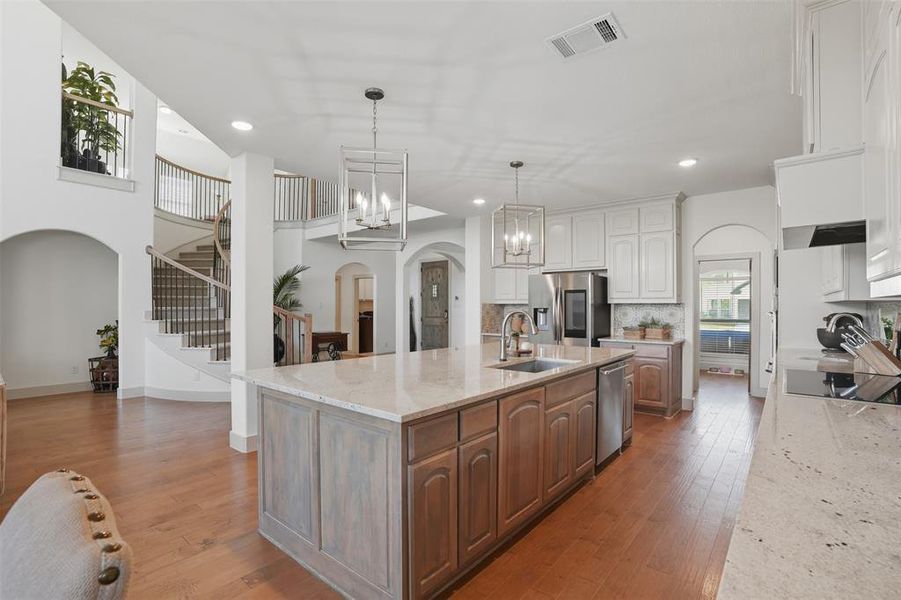 Kitchen with arched walkways, backsplash, light wood-style flooring, a chandelier, and recessed lighting Kitchen with arched walkways, backsplash, light wood-style flooring, a chandelier, and recessed lighting